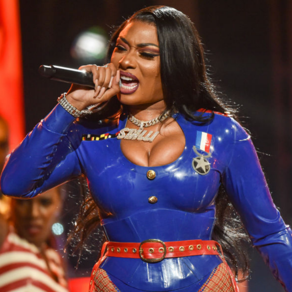 Megan Thee Stallion tenant un micro Learn English With Music habillé d'une combinaison bleu